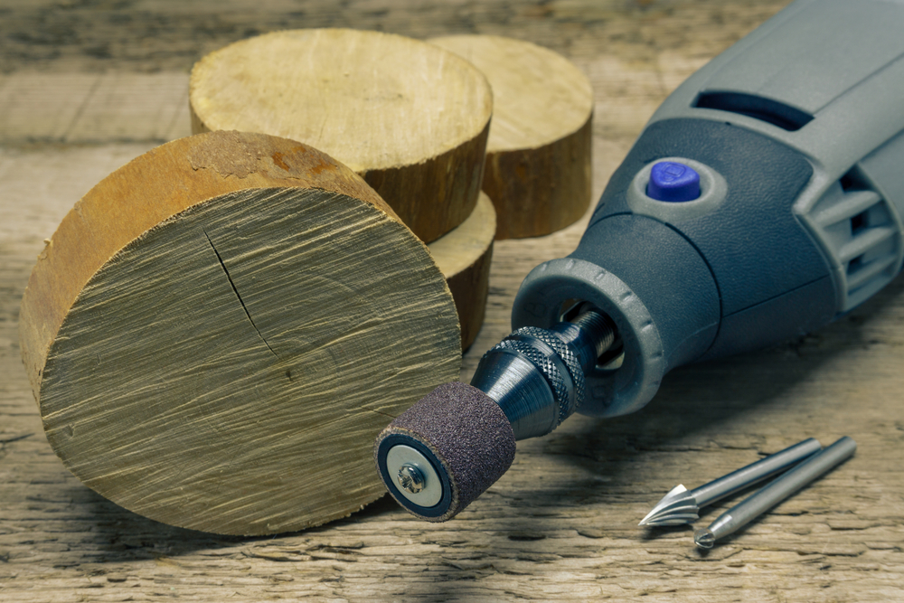 A dremel tool on a table with two bits and some wood
